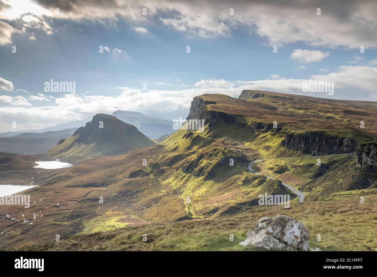 Il Quiraing sull'isola di Skye sotto cieli spettacolari, con aspre colline verdi, strade tortuose e laghi lontani che creano un iconico paesaggio delle Highland Foto Stock