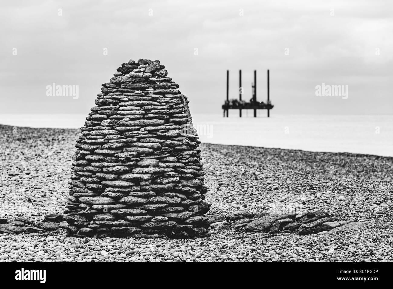 Un cairn a forma di alveare fatto di pietre impilate su una spiaggia di ciottoli, che fonde materiali naturali ed espressioni artistiche sulla costa britannica. Foto Stock