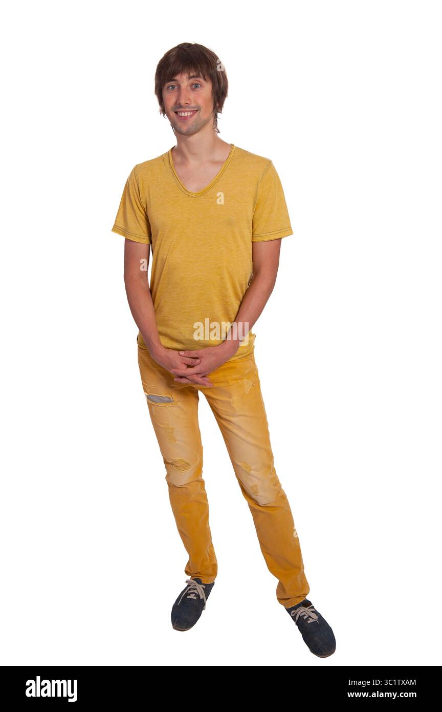 Un giovane uomo si staglia con una posa rilassata, indossando una camicia gialla brillante e un paio di jeans. Foto Stock