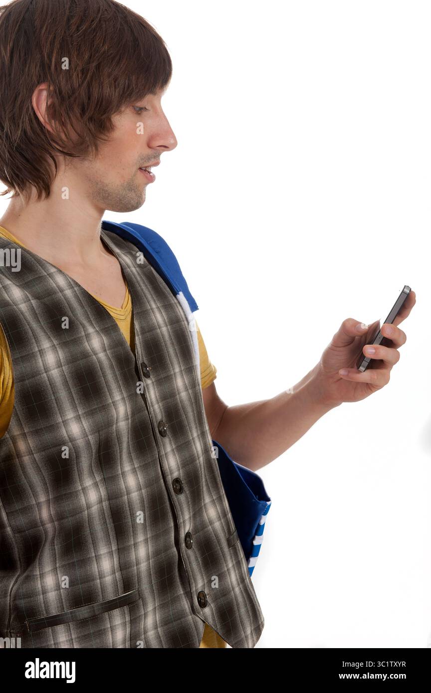 Un uomo con un gilet elegante si impegna con il suo smartphone, perso nel pensiero. Foto Stock