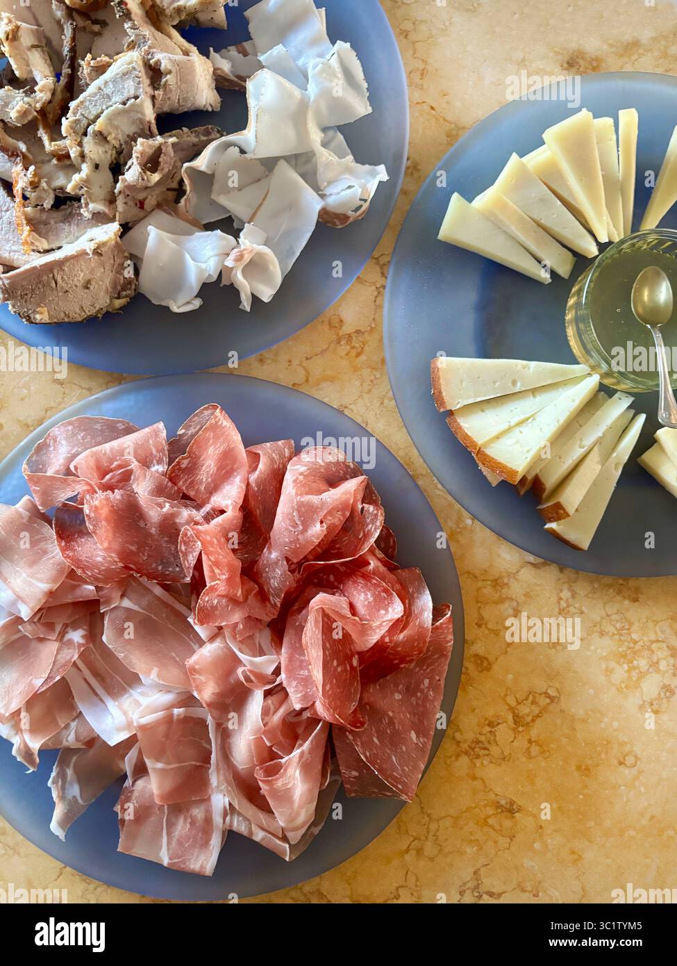 Tagli di salato prosciutto, salame e formaggio tipici italiani in piatti blu in tavola. Cucina tradizionale italiana. Direttamente sopra. Foto Stock