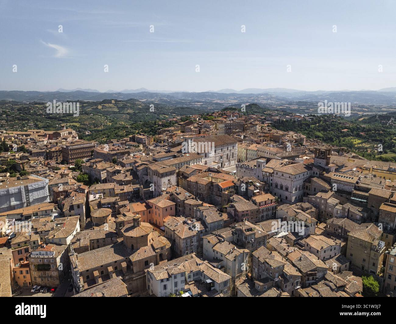Vista aerea dei tetti illuminati dal sole e degli antichi edifici che si fondono perfettamente con le dolci colline in lontananza, Perugia, Umbria, Italia. Foto Stock