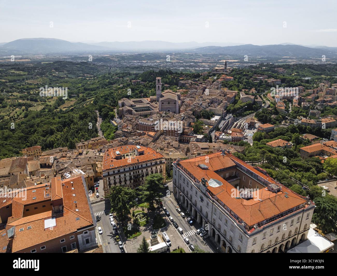 Vista aerea dei tetti in terracotta che scendono lungo la collina verso i grandi edifici e la lontana Basilica di San Pietro, Perugia, Umbria, Italia. Foto Stock