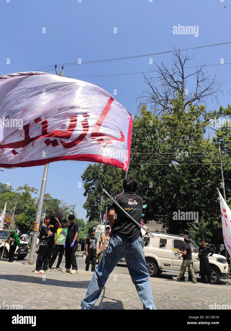 Un musulmano sciita del Kashmir che sfocia bandiere durante l'VIII Processione muharram a M.A Road srinagar, 4 luglio 2025 Foto Stock