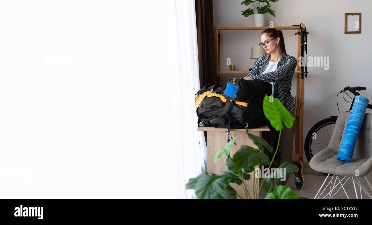 escursionismo, preparazione di uno zaino per un viaggio in montagna, escursionista che si prepara per un tour naturalistico a casa. copia spazio. banner Foto Stock