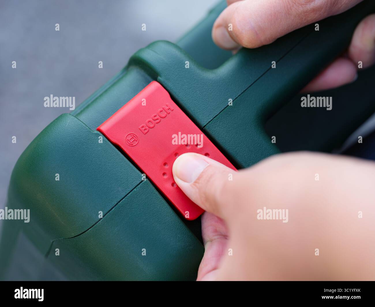 Tambov, Federazione Russa - 06 luglio 2025 apertura a mano del fermo rosso della valigetta portautensili Bosch verde. Primo piano. Foto Stock