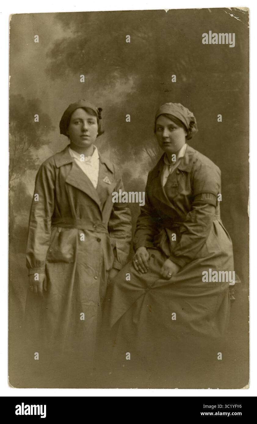 Era della prima Guerra Mondiale molto chiara, cartolina di 2 donne operaie di munizioni, amici che indossano l'uniforme, pantaloni, berretti. Entrambi hanno i distintivi del servizio di guerra sui revers e la ragazza sul lato destro ha una fascia da braccio M.I.D. (Munitions Inspectorate Department), Regno Unito circa 1916-1918. Foto Stock