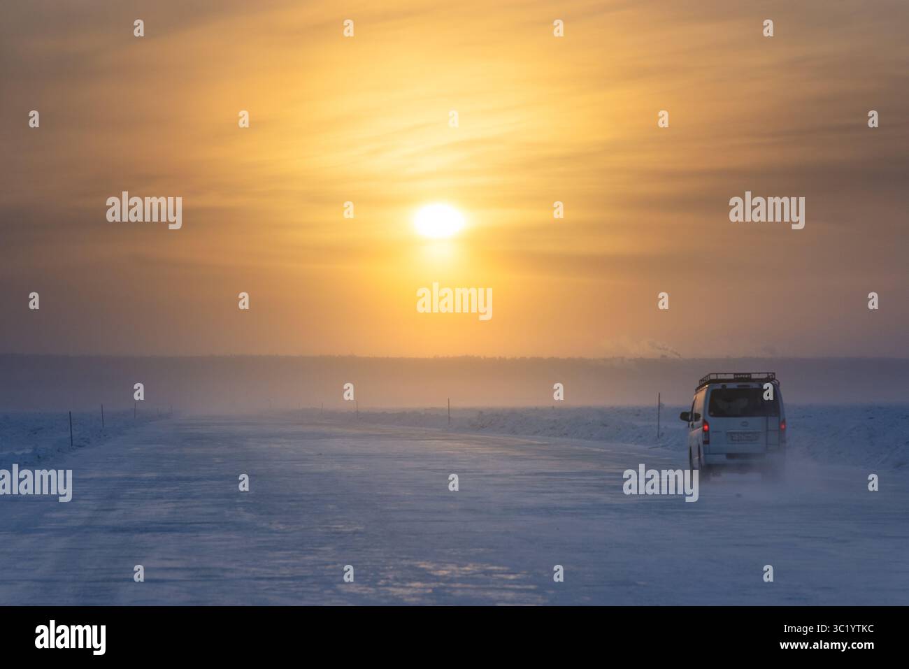 Fiume Lena, Russia - 23 luglio 2025: La vista di un veicolo solitario naviga su una vasta pianura innevata sotto un sole radioso e etereo, dietro di essa la polvere. Foto Stock
