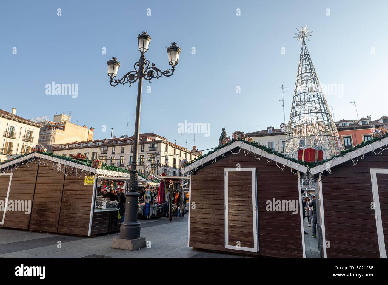 Madrid, Spagna. Bancarelle del mercatino di Natale allestite in Plaza de Isabel II, con edifici residenziali sullo sfondo, che catturano l'atmosfera stagionale A. Foto Stock