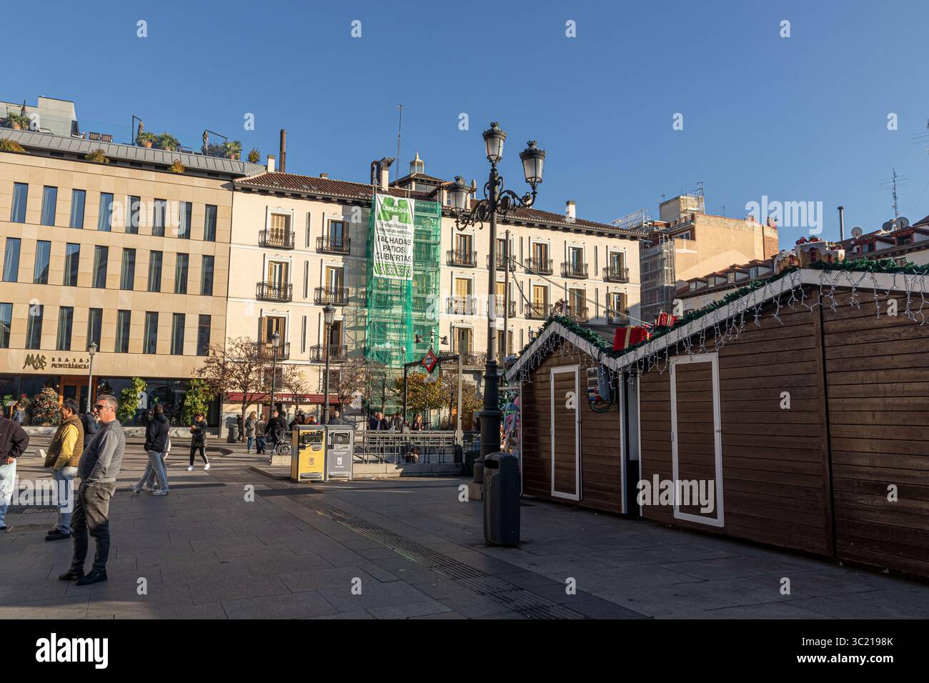 Madrid, Spagna. Bancarelle del mercatino di Natale allestite in Plaza de Isabel II, con edifici residenziali sullo sfondo, che catturano l'atmosfera stagionale A. Foto Stock