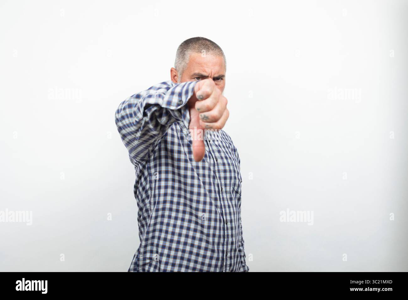 Uomo maturo che mostra un cartello con il pollice giù, esprime disapprovazione e feedback negativo Foto Stock