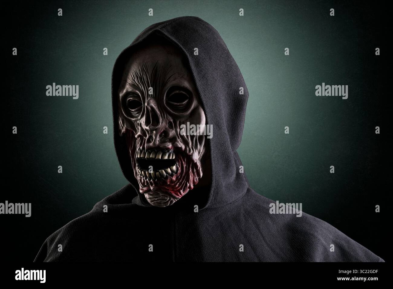 Ritratto di uno zombie con mantello con cappuccio su sfondo verde scuro e nebbioso Foto Stock