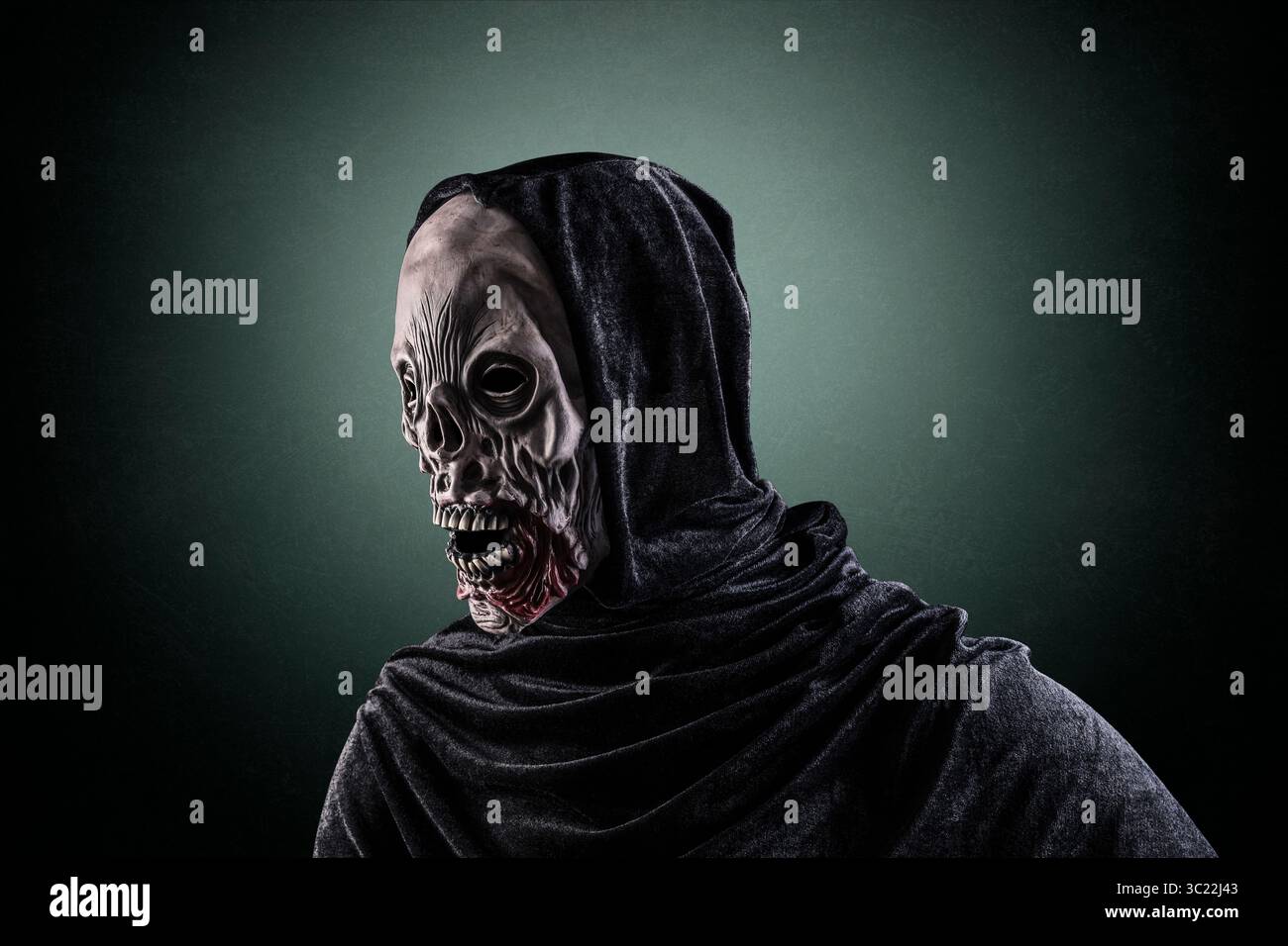 Ritratto di uno zombie con mantello con cappuccio su sfondo verde scuro e nebbioso Foto Stock