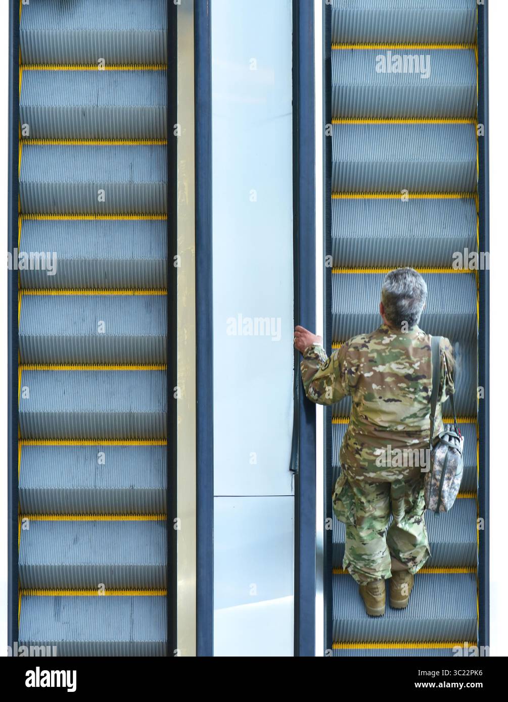 Scala mobile con uomo in camuffamento, abbigliamento militare. Foto Stock