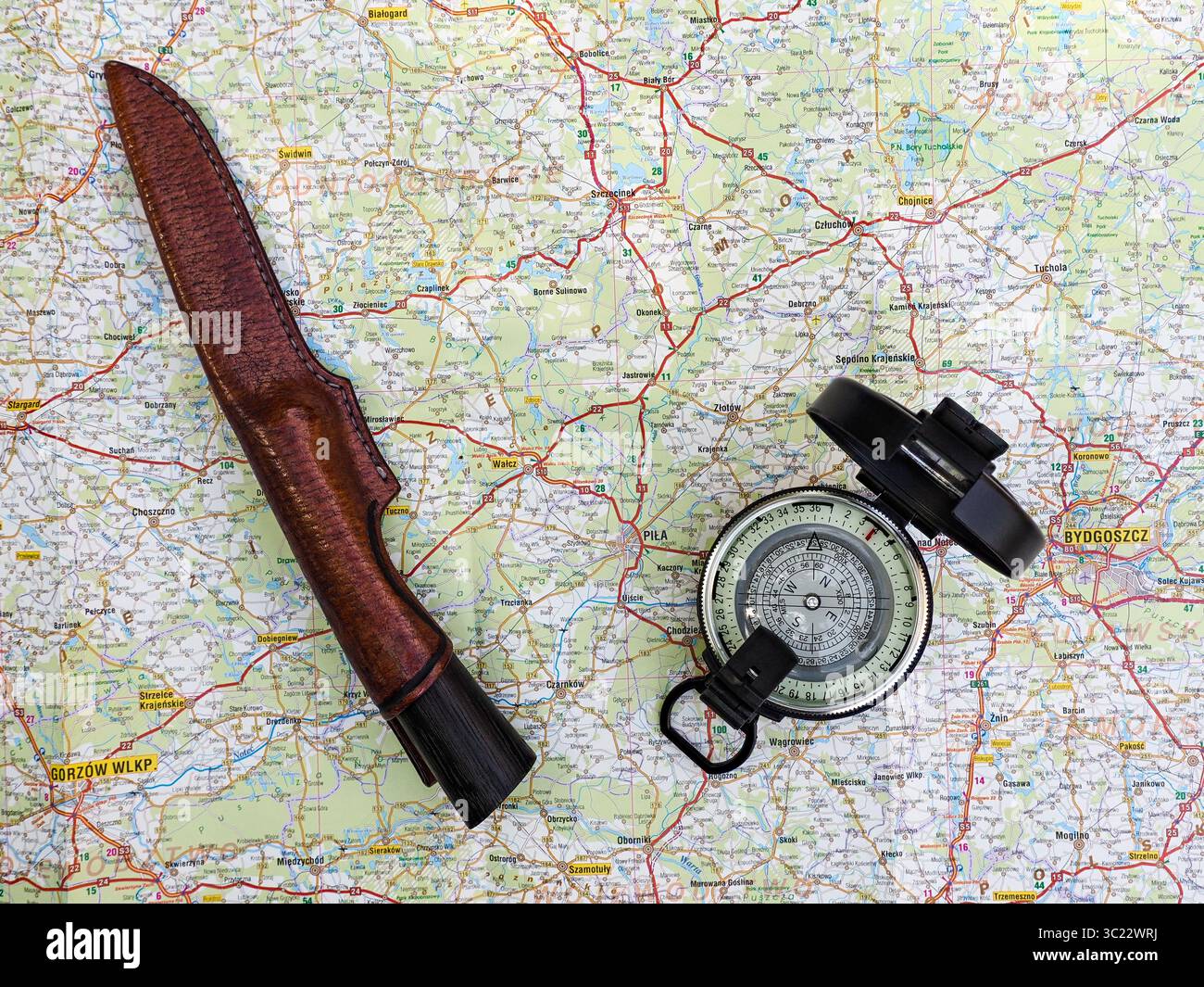 Mappa con strade e città con bussola di navigazione e coltello, che rappresentano l'equipaggiamento di viaggio, esplorazione e avventura. Ideale per la sopravvivenza, o Foto Stock
