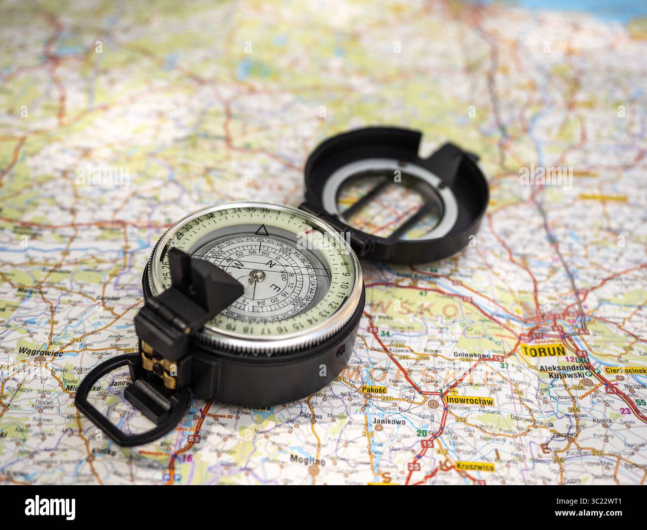 Una bussola all'aperto posizionata su una mappa dettagliata che mostra navigazione, esplorazione e pianificazione. Ideale per il trasporto di concetti di marcia, direzione e. Foto Stock