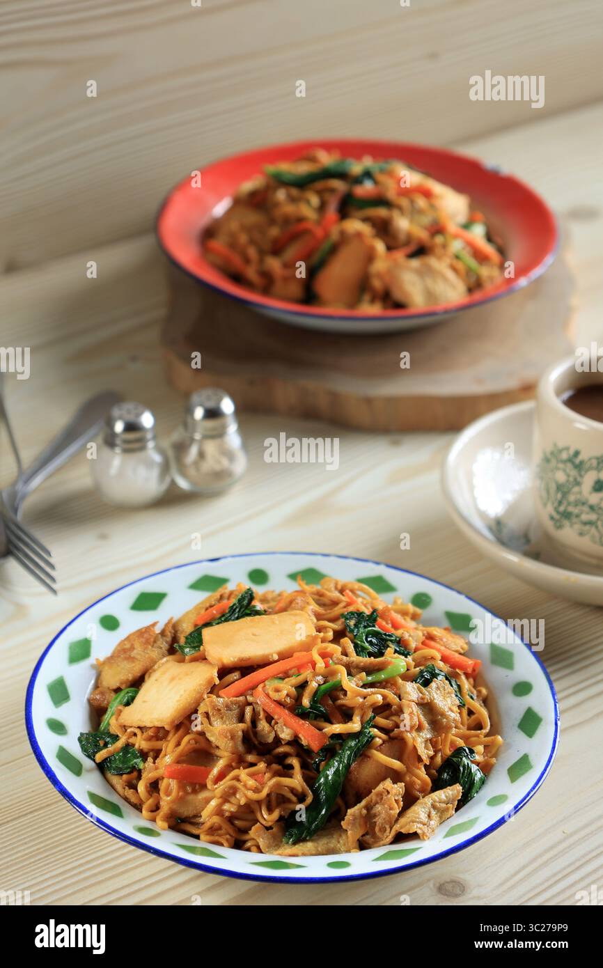 Telo indonesiano mie Goreng con verdure e uova, menu giornaliero servito su piatto di smalto. Spaghetti indonesiani fritti in padella Foto Stock