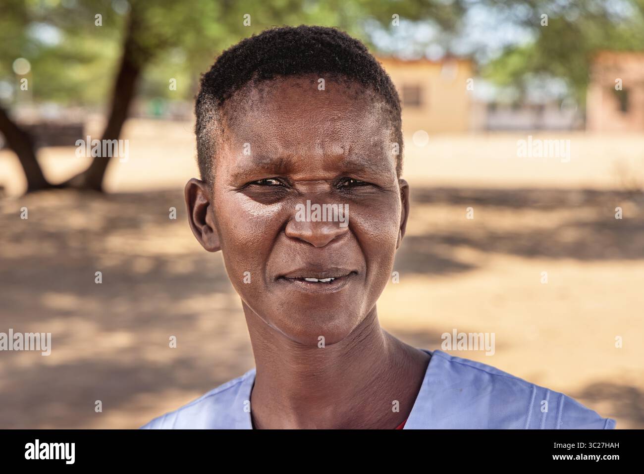 ritratto alla testa di una donna africana single nel villaggio, felice con un sorriso toothy, capelli corti, all'aperto Foto Stock