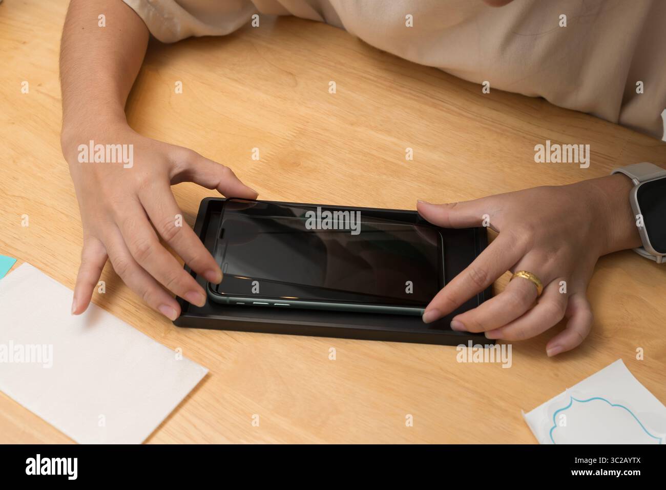 Primo piano delle mani allineando con attenzione la protezione dello schermo in vetro temperato allo smartphone. Fase finale dell'installazione della protezione dello schermo. Fai da te Foto Stock