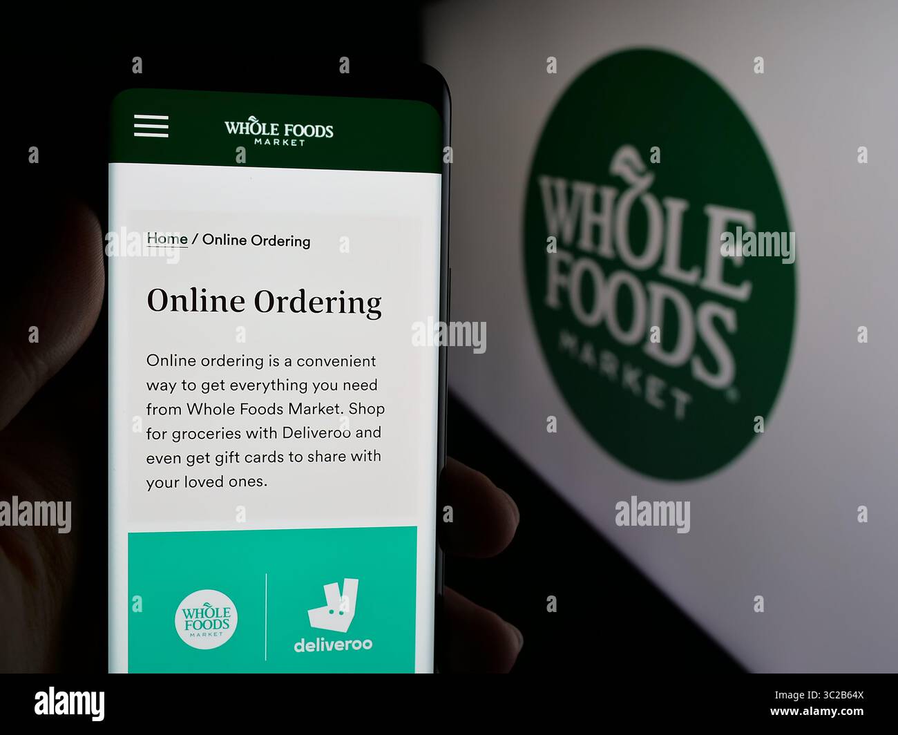 Stoccarda, Germania - 05-25-2025: Persona che possiede uno smartphone con pagina Web della società statunitense di vendita al dettaglio Whole Foods Market Inc. Sullo schermo davanti al logo. Foto Stock