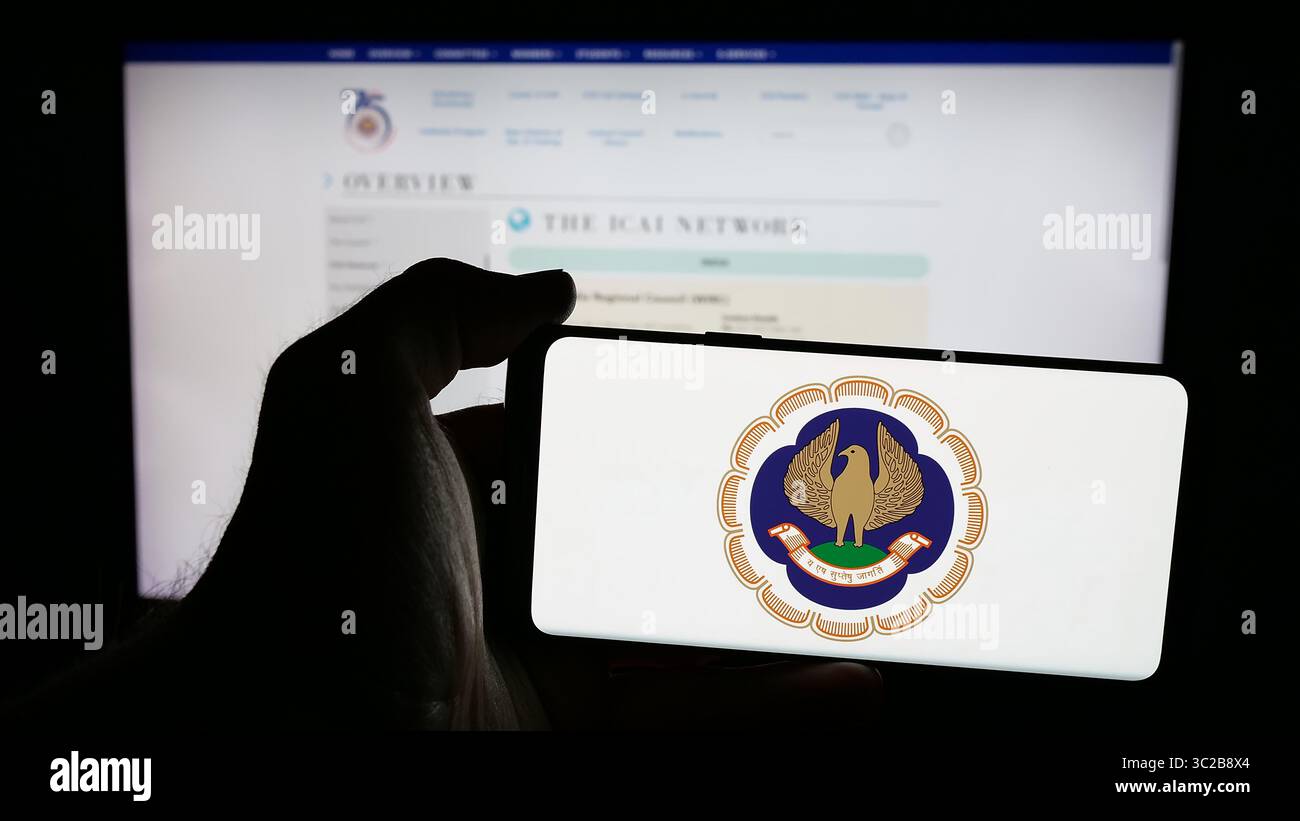 Stoccarda, Germania - 05-29-2025: Persona che possiede un telefono cellulare con il logo dell'Istituto dei Dottori Commercialisti (ICAI) sullo schermo di fronte alla pagina web. Foto Stock