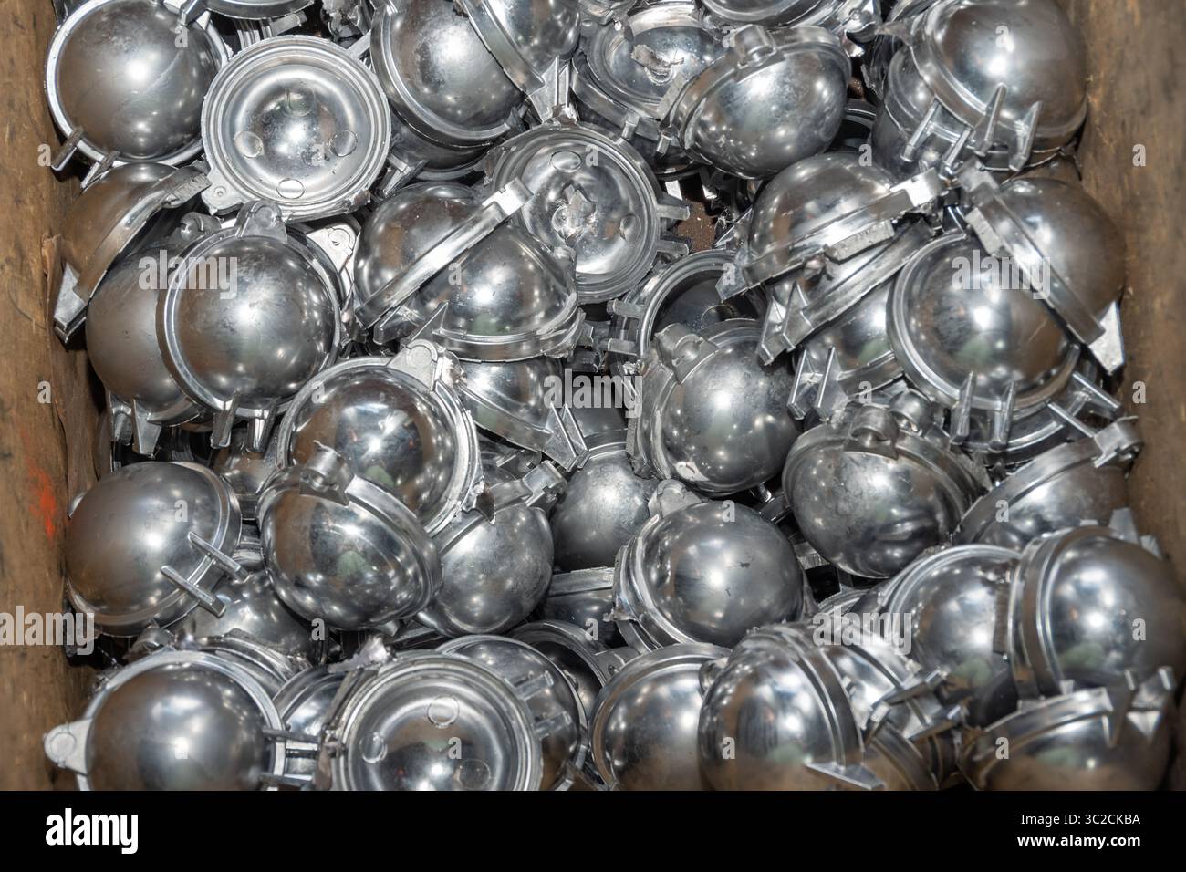 Parti metalliche lucide in pile, stile industriale, collocate in una scatola di legno. Concetto di produzione o riciclaggio dei materiali Foto Stock