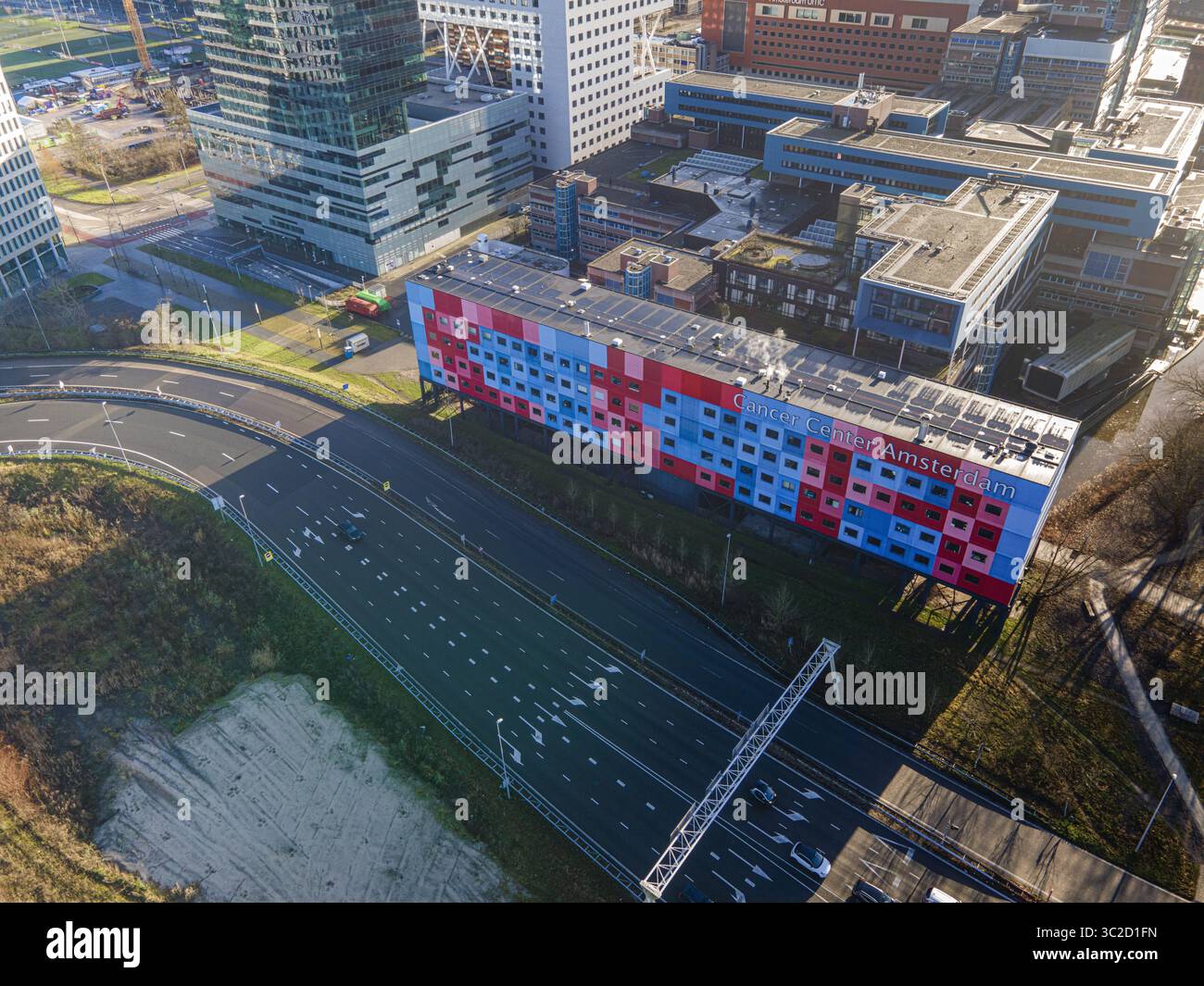 La vista aerea di un edificio colorato vicino a un'autostrada a più corsie riflette la vivacità urbana in mezzo all'architettura moderna, Amsterdam, Olanda settentrionale, Paesi Bassi. Foto Stock
