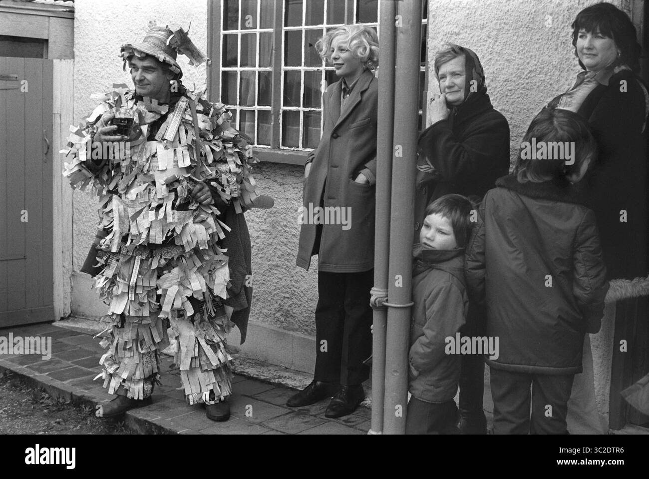 Drink di birra durante il periodo natalizio. Crookham Mummers Boxing Day 26 dicembre 1974 gli abitanti del villaggio guardano le partite folcloristiche, mentre un membro della squadra di mumming beve una pinta del giorno di Santo Stefano, in piedi fuori dal pub del villaggio. Crookham, Hampshire, Inghilterra Regno Unito 1970s HOMER SYKES Foto Stock