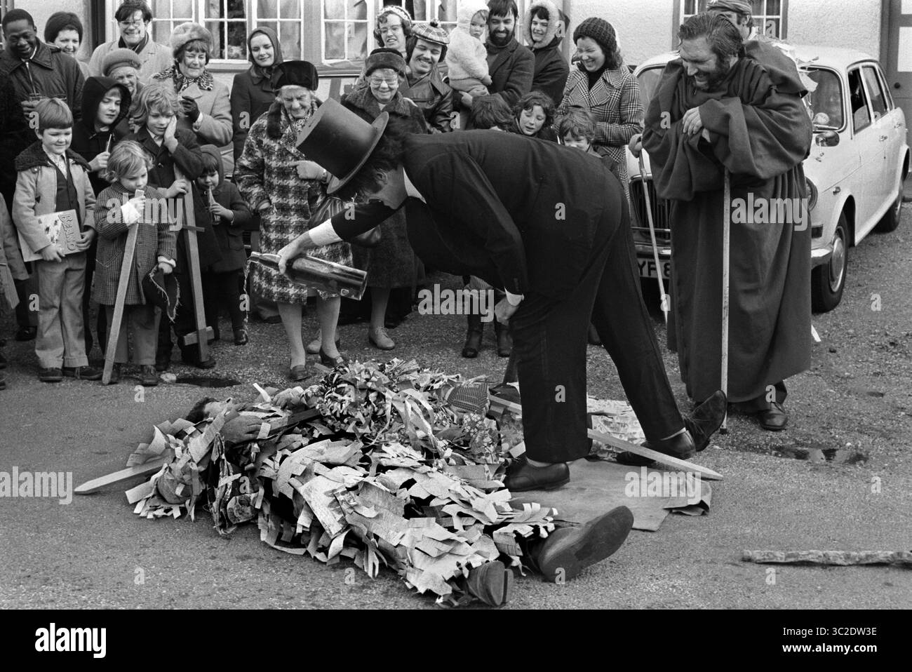 Morte rituale e risurrezione il giorno di Santo Stefano tradizionale gioco popolare. I Crookham Mummers 26 dicembre 1974. Il Dottore Quack in cappello, ravviva due combattenti con una goccia di qualcosa di forte. Il pubblico del villaggio guarda divertito. Crookham, Berkshire, Inghilterra Regno Unito 1970s HOMER SYKES Foto Stock