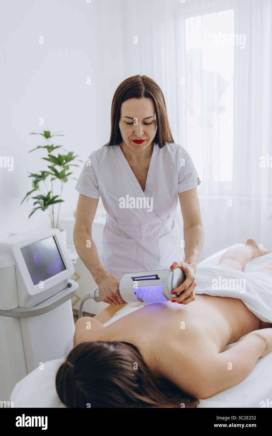 Il cosmetologo esegue la terapia endosferica sulla schiena della donna. Massaggio anticellulite, correzione delle figure, drenaggio linfatico, trattamento non invasivo in BE Foto Stock