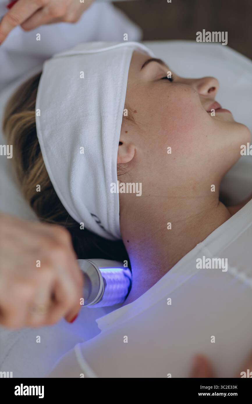 Una giovane donna che riceve un rilassante massaggio terapeutico endosferico sulla spalla in una clinica di bellezza. Trattamento corporeo non invasivo per il tono muscolare AN Foto Stock