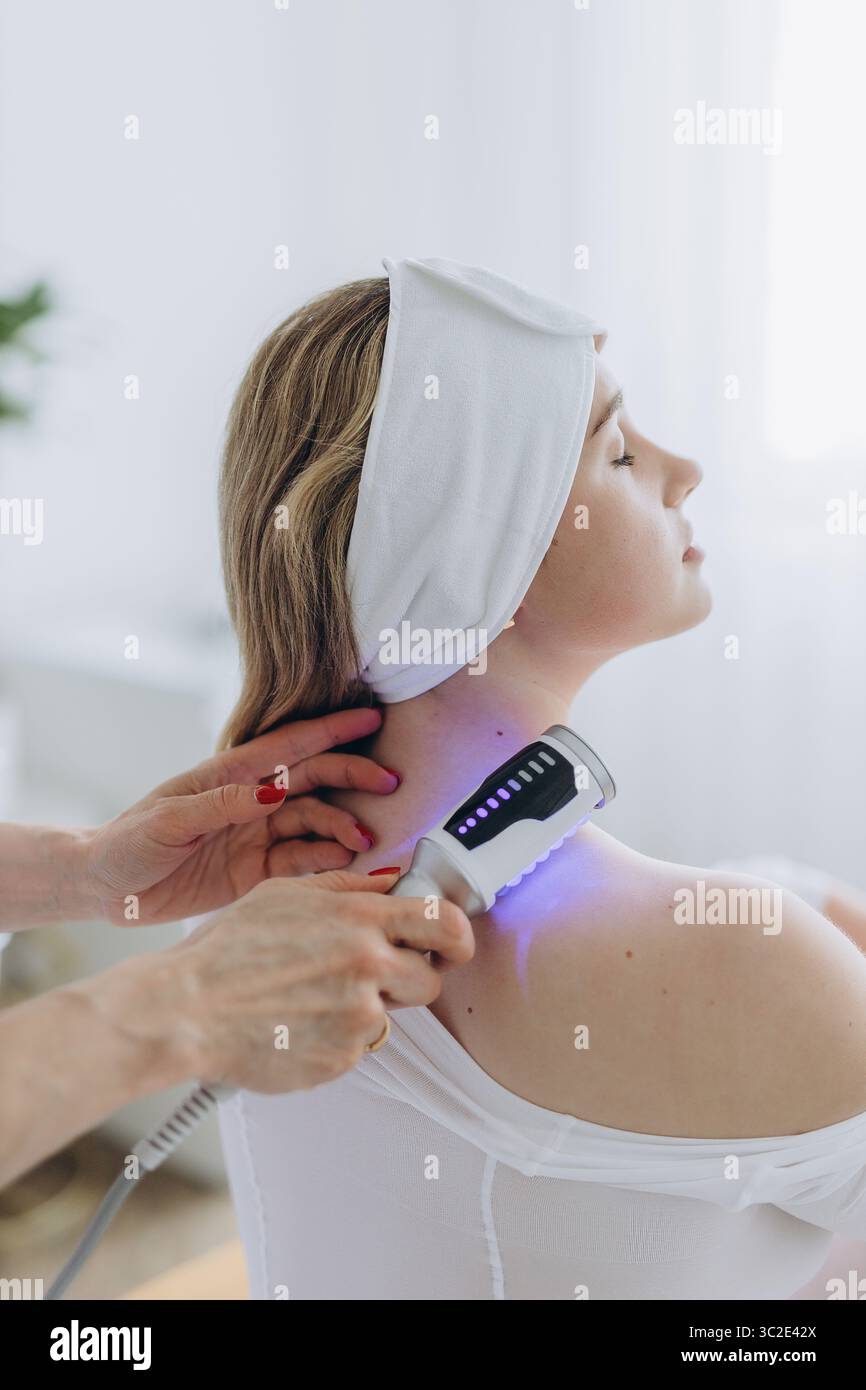 Una giovane donna che riceve un rilassante massaggio terapeutico endosferico sulla spalla in una clinica di bellezza. Trattamento corporeo non invasivo per il tono muscolare AN Foto Stock