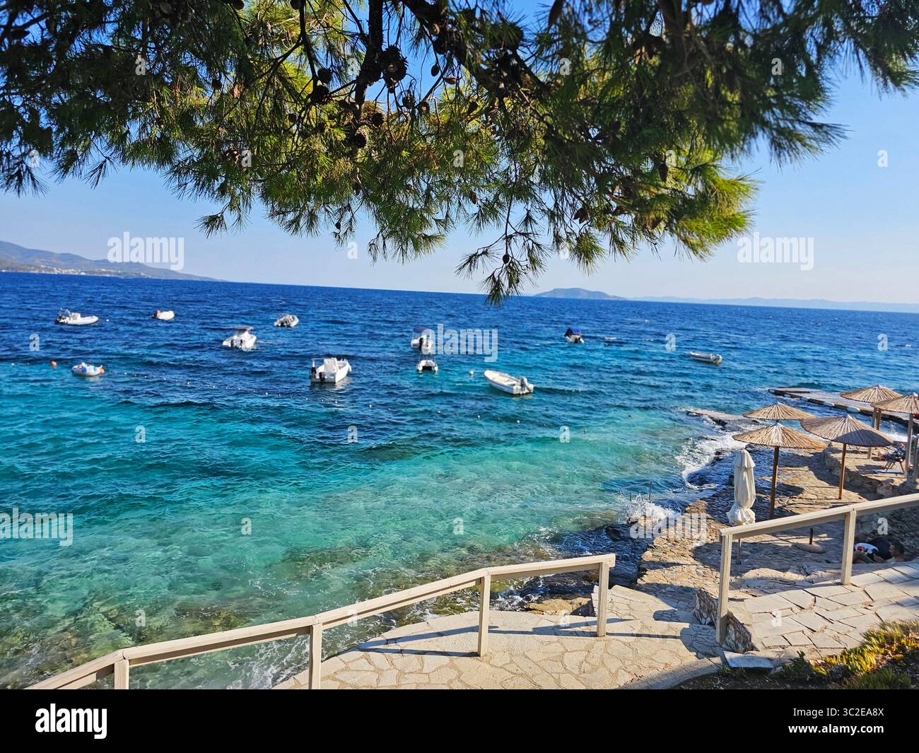 Vista panoramica sulla costa con barche attraccate nelle acque cristalline turchesi di Salonic, Grecia - Immagine stock catturata con smartphone