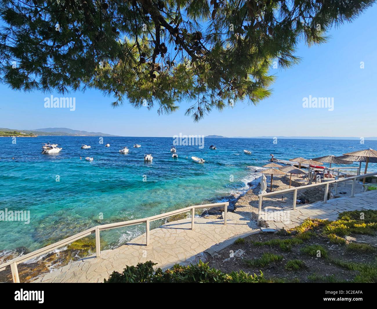 Vista panoramica sulla costa con barche attraccate nelle acque cristalline turchesi di Salonic, Grecia - Immagine stock catturata con smartphone