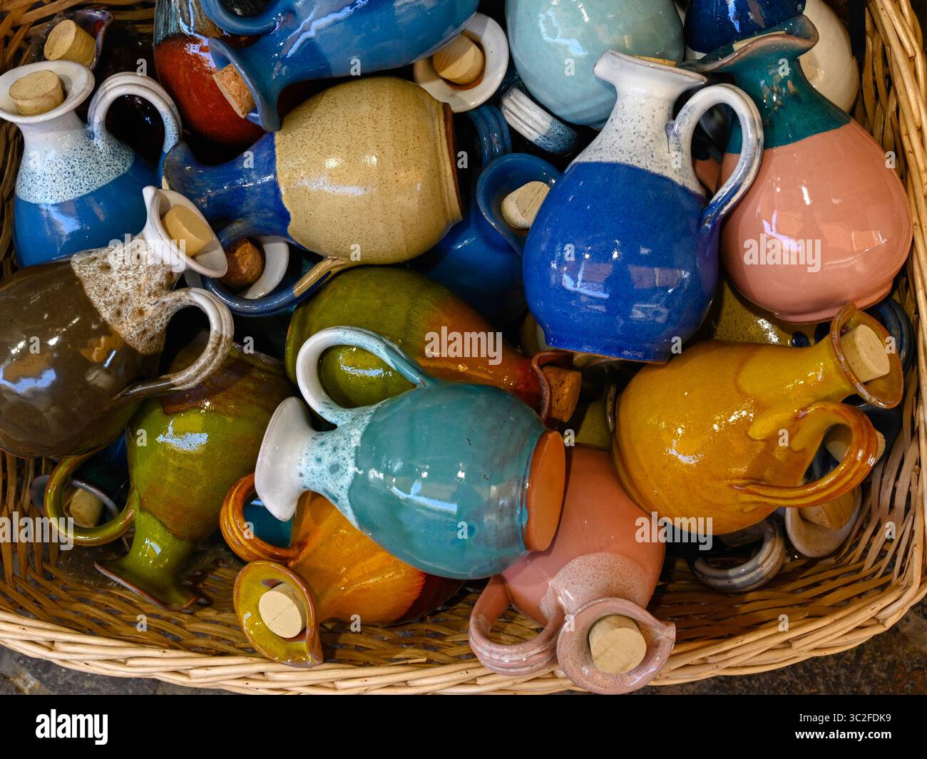Bottiglie di olio in ceramica colorate in un cestino all'esterno di un negozio di souvenir Foto Stock