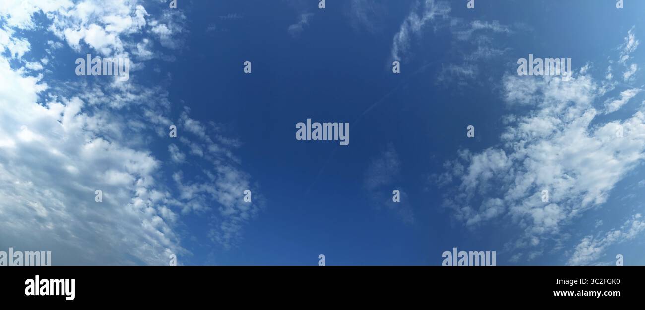Cielo blu luminoso e sereno adornato da nuvole bianche e soffici e una formazione panoramica. Foto Stock
