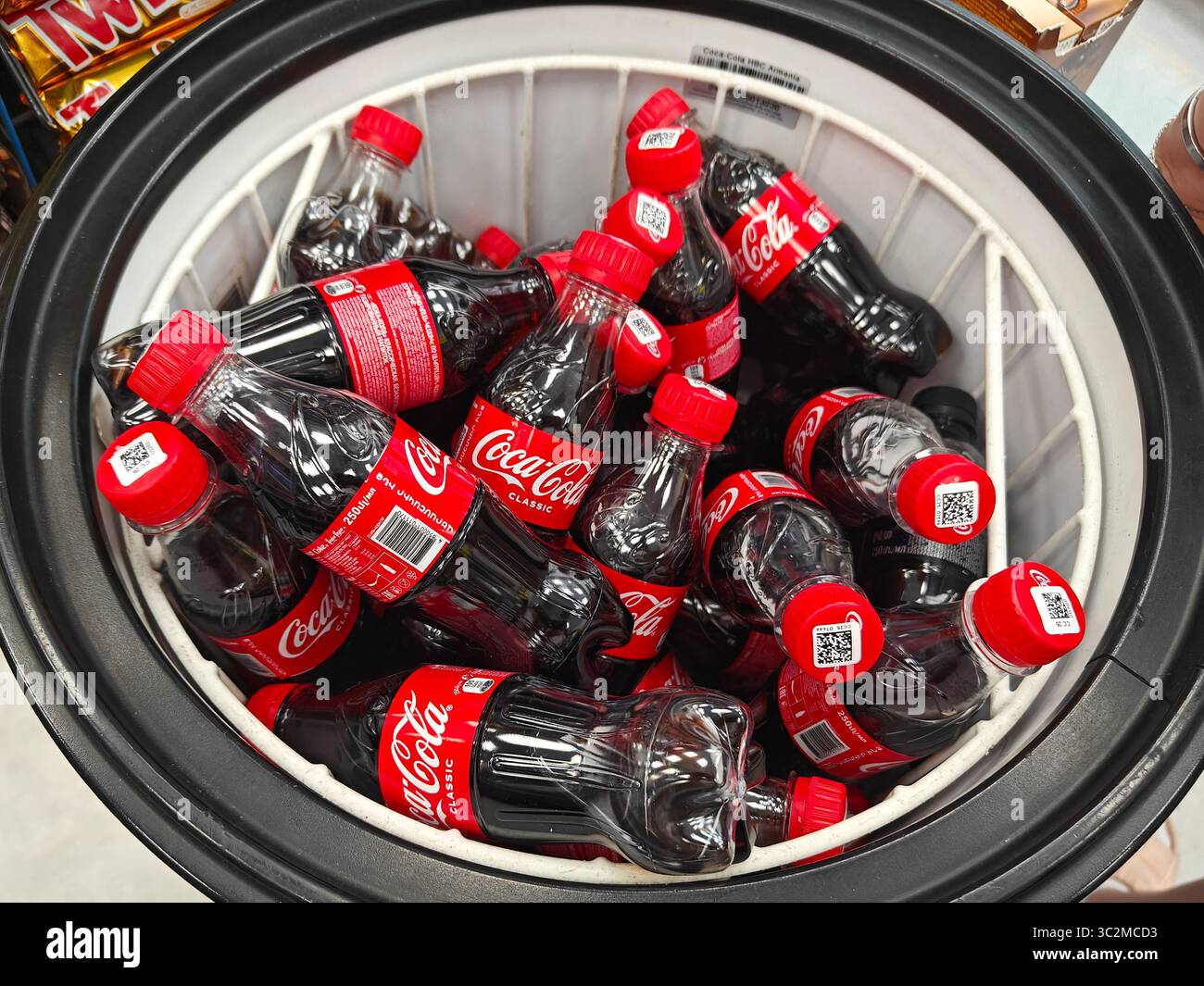 Erevan, Armenia - 17 luglio 2025: Bottiglie di Coca-Cola sono confezionate in un frigorifero circondato da ghiaccio e spuntini Foto Stock