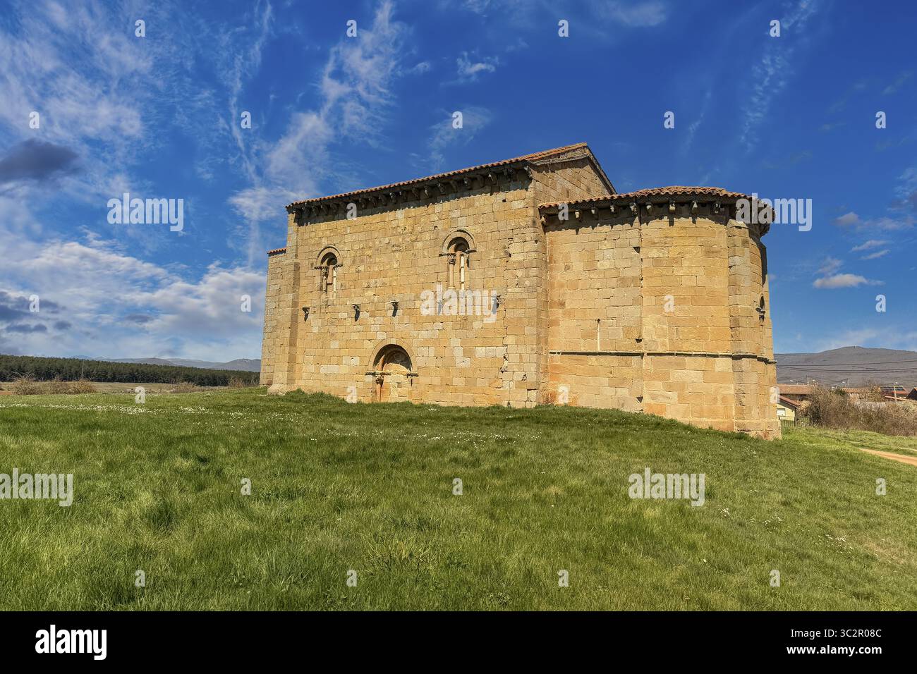 Storica chiesa romanica di San Martino a Matalbaniega, Spagna, con mura in pietra e un campanile sotto un cielo azzurro Foto Stock