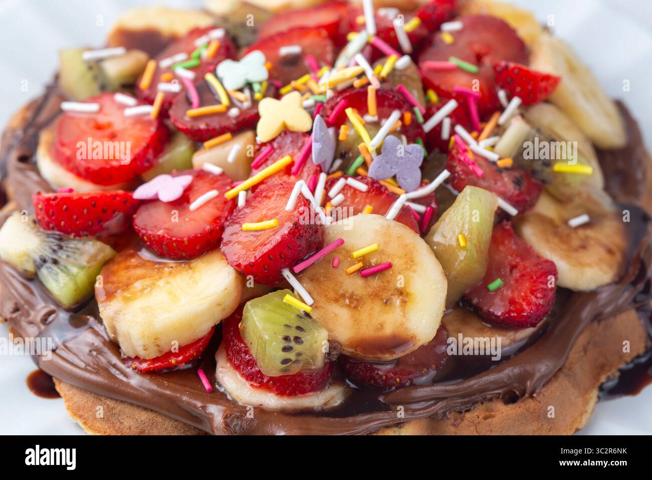 Waffle alla frutta, banane al cioccolato, fragole, patatine al cioccolato, waffle turchi fatti a mano e pistacchi Foto Stock
