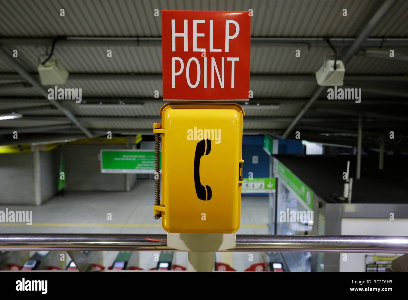Il telefono di emergenza è visto accanto ai pendolari in una stazione ferroviaria della metropolitana di Kuala Lumpur, Malesia. Foto Stock