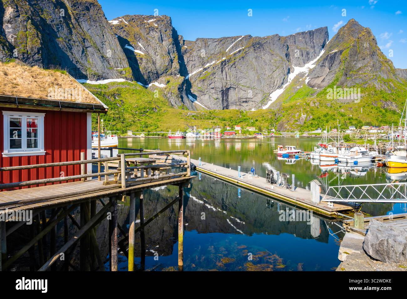 Vista di case e barche nel porto e villaggio di Reine, mare e montagne sull'isola di Moskenesoy in estate, isole Lofoten, Norvegia Foto Stock