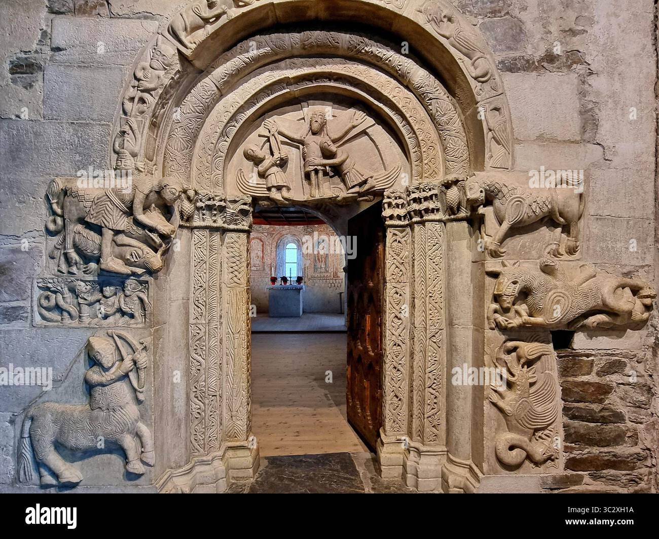 Portale in marmo romanico della Cappella di San Pancrazio sculture simboliche e mitiche nel castello medievale di Tirolo, Italia Foto Stock