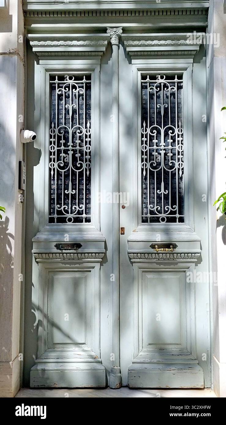 Una porta frontale in legno a doppia foglia decorata con un ornamento forgiato aperto, sulla facciata di un edificio nel centro storico di Atene, Grecia Foto Stock