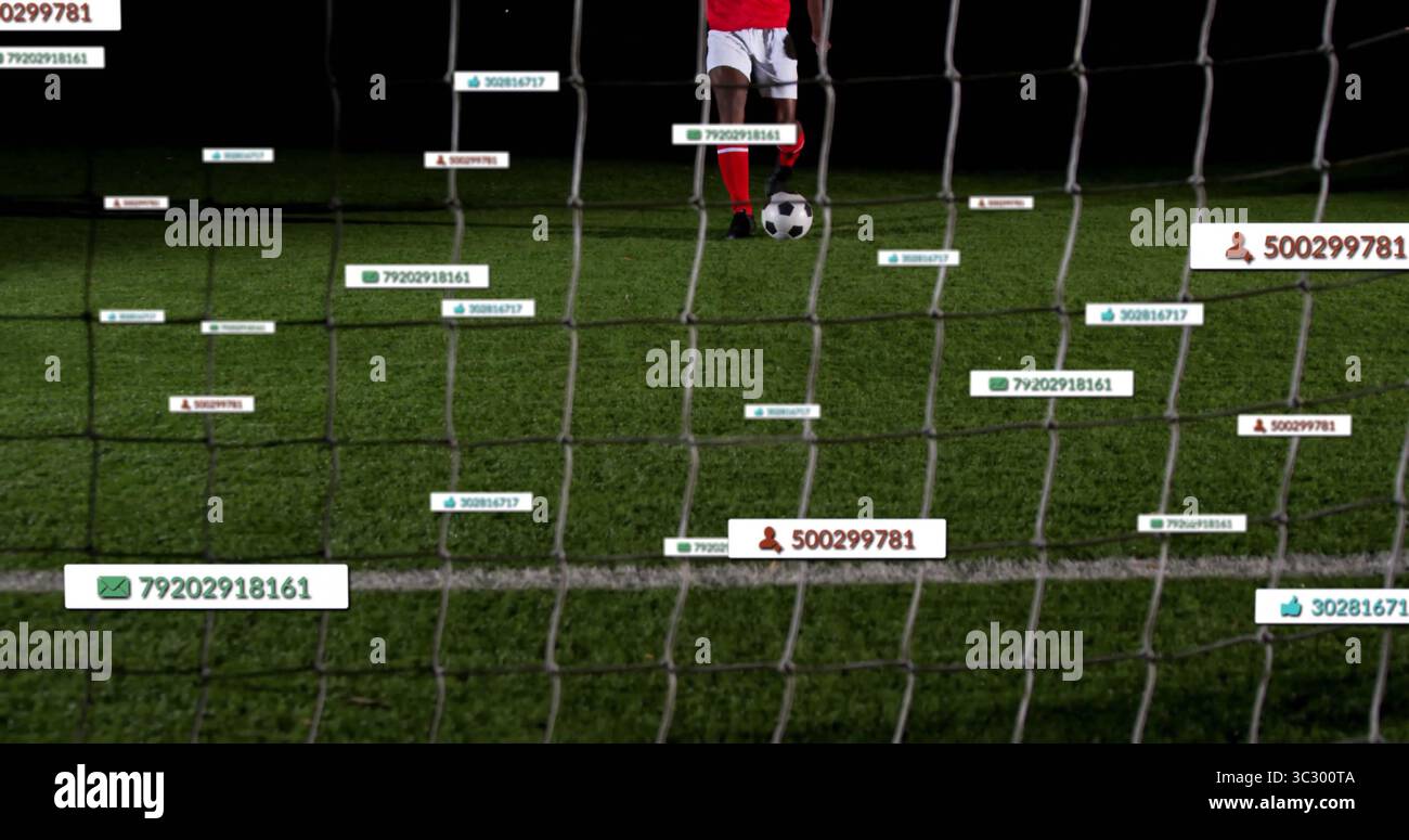 Giocatore di calcio in maglia rossa che si prepara a calciare sul campo notturno, con rete porta, cartellini Foto Stock