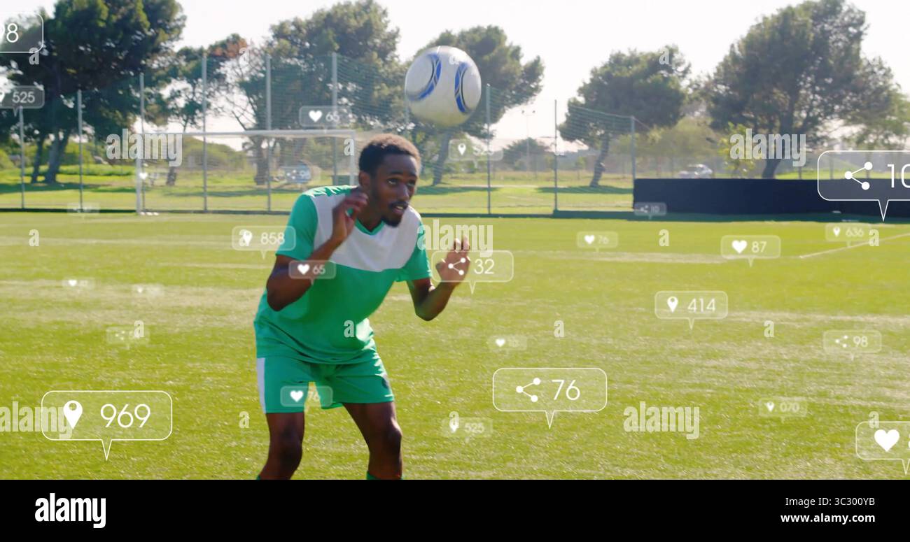 Giocatore di calcio che salta in maglia verde dirigendo palla di calcio bianco-blu su campo di erba, con sovrapposizioni Foto Stock