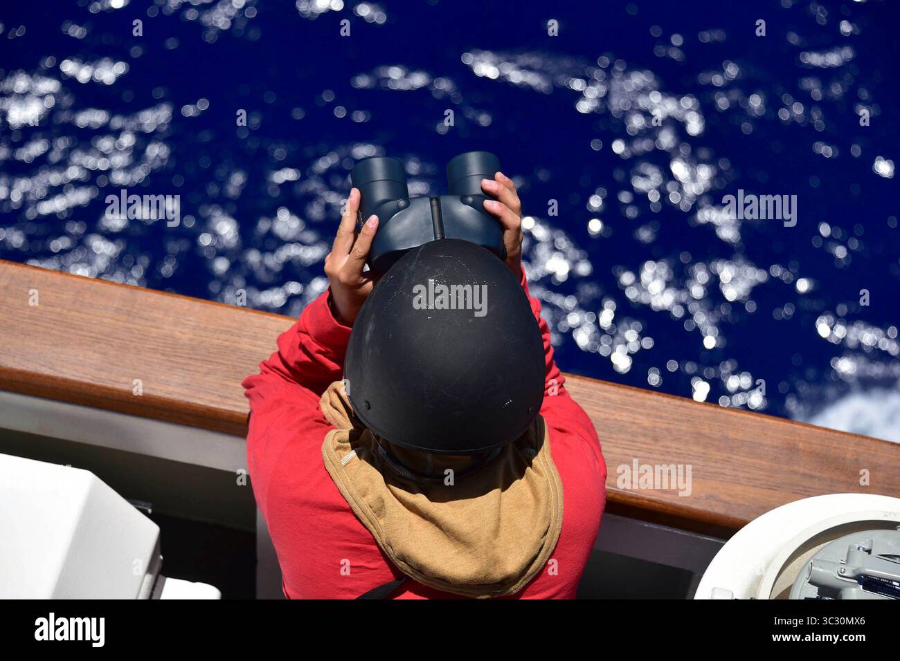 19 agosto 2019 - At Sea - Un membro dell'equipaggio a bordo della Guardia Costiera Cutter Kimball (WMSL 756) si trova a guardare sull'ala del ponte di dritta con equipaggiamento flash e un casco balistico mentre la nave si prepara a sparare il suo Mk-110 57 mm per la prima volta 19 agosto 2019. La nave, la settima National Security Cutter ad essere acquistata dalla Guardia Costiera, è prevista per una cerimonia unica a doppia messa in servizio con la Guardia Costiera Cutter Midgett (WMSL 757), l'ottava NSC, presso il nuovo porto di cutters’ a Honolulu il 24 agosto 2019. (Immagine di credito: © U.S. Coast Guard/ZUMA Wire/ZUMAPRESS.com) Foto Stock