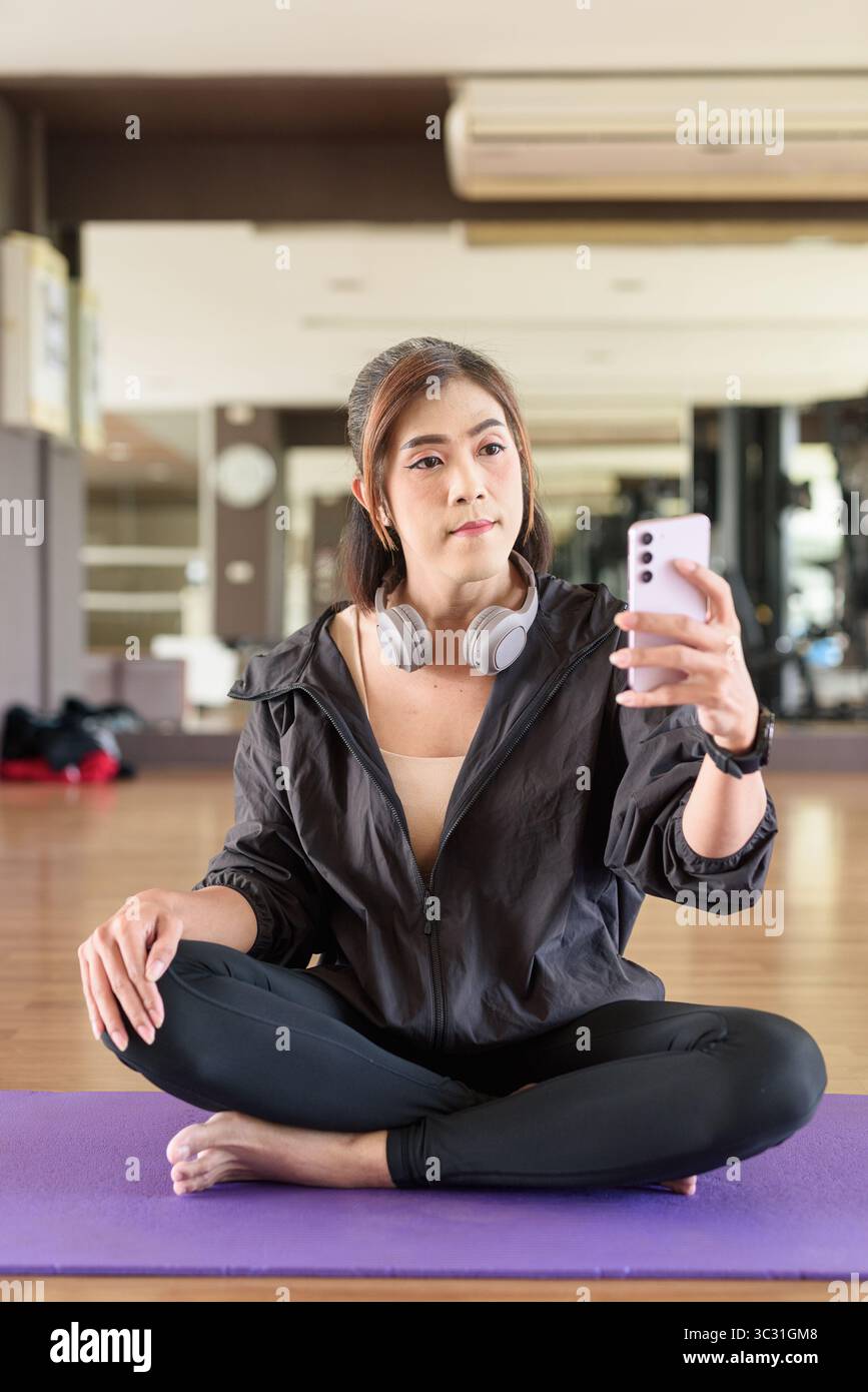 Donna transgender negli anni '40 pratica yoga in un ambiente fitness in palestra, che rappresenta flessibilità, equilibrio e benessere Foto Stock