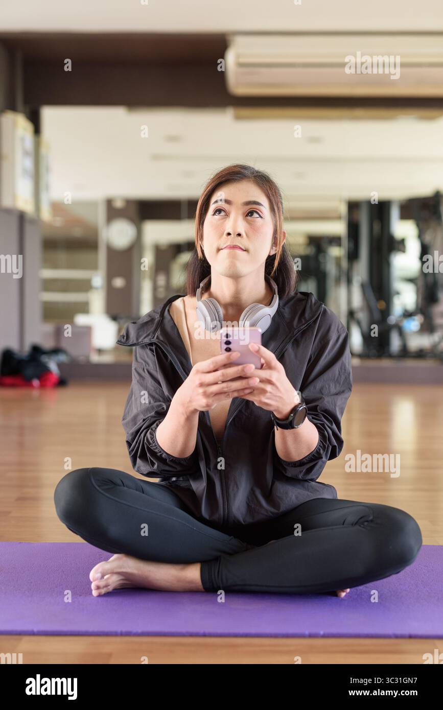 Donna transgender negli anni '40 pratica yoga in un ambiente fitness in palestra, che rappresenta flessibilità, equilibrio e benessere Foto Stock