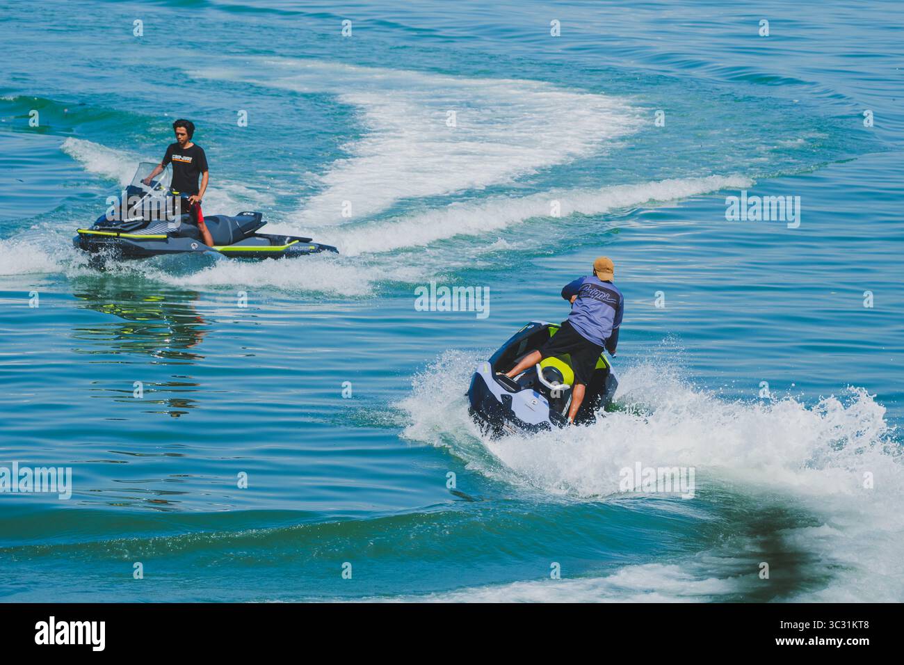 Balikpapan, Indonesia - 4 maggio 2025. Due uomini manovrano moto d'acqua attraverso l'oceano azzurro, lasciandosi alle spalle percorsi d'acqua dinamici. Foto Stock