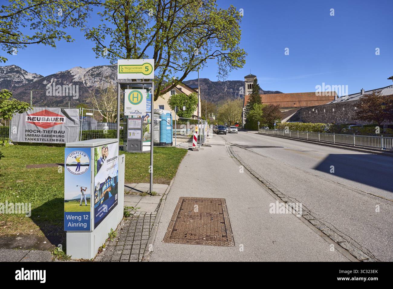 Fermata dell'autobus Kirchberger Bahnhof - Lattengebirge, architettura generale, alberi, chiesa, scatola di commutazione, paesaggio montano, montagne, cielo blu, nuvoloso, nutrito Foto Stock